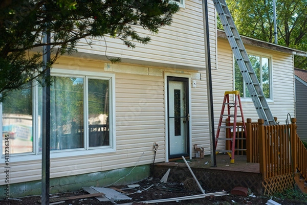 Fototapeta Installation of new vinyl siding is nearing completion on the front of a split-level house.