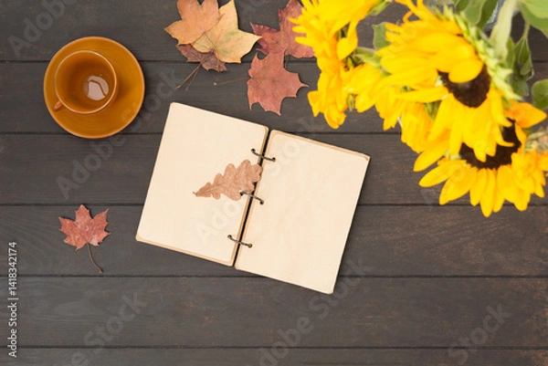 Fototapeta Open notebook with bouquet of sunflowers and empty brown cup on wooden table