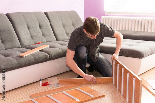 Obraz Picture how man made furniture in the living room. Hard work manager. Desperate man can not build a commode. Young man assembling furniture. Handyman building furniture in the living room.