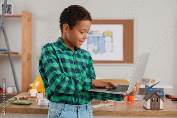 Fototapeta Cute little architect with laptop at home