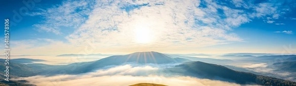 Fototapeta Panoramic view of Carpathian Mountains with foggy valley and sunlight on mountain peak under vibrant blue sky with clouds, wide high-resolution morning landscape background