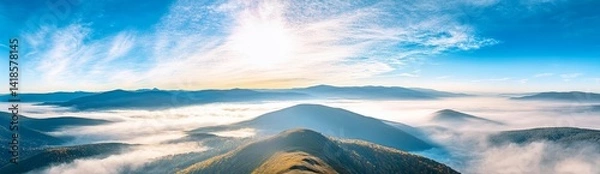 Fototapeta Panoramic view of Carpathian Mountains with foggy valley and sunlight on mountain peak under vibrant blue sky with clouds, wide high-resolution morning landscape background