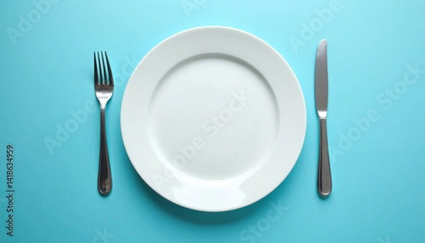 Fototapeta A white plate with a fork and knife on a blue background.