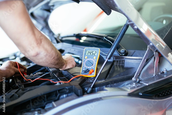 Fototapeta Auto mechanic repairing car. Selective focus on hand. 