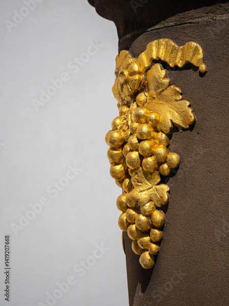 Obraz Close-up of a golden grapevine sculpture on a metal surface.