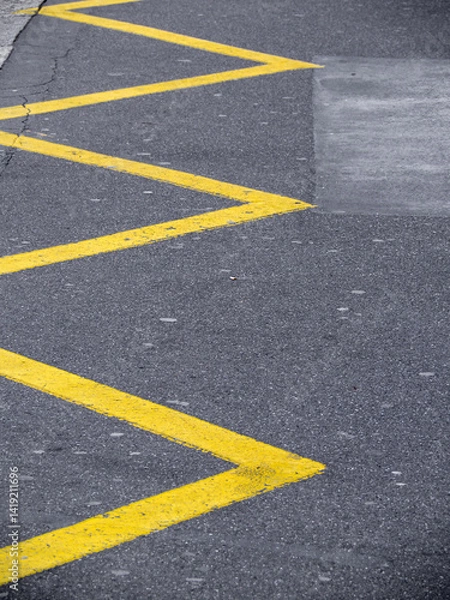Obraz Close-up of a road with yellow zigzag lines painted on the asphalt.
