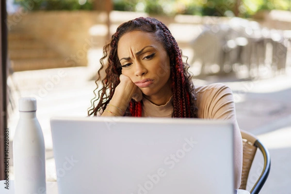 Fototapeta A Focused Woman Intently Working on Her Laptop While Exhibiting a Concerned Expression on Her Face