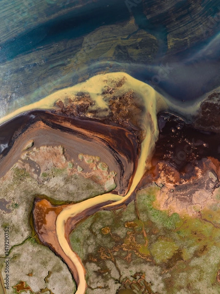 Obraz Abstract aerial of a delta where yellow and black sediments meet the deep blue sea, forming organic shapes and colorful contrasts in the coastal wetland.