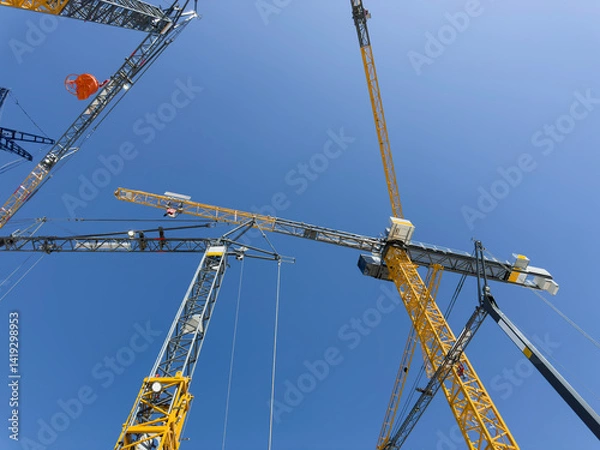 Fototapeta Construction cranes. View from below. Crane used to construct palaces, houses or buildings. Construction site. General contest
