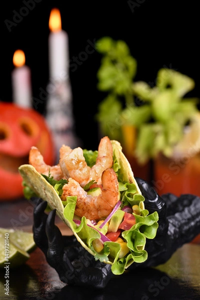 Fototapeta Black monster hand holding tacos crispy fried shrimp. Halloween party serving