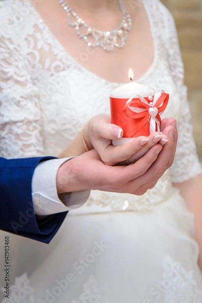 Fototapeta The bride and groom holding a candle