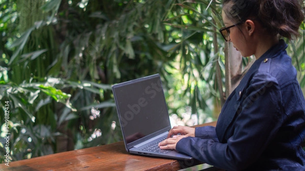 Fototapeta Businesswoman working on laptop on rich tree background in cafe, freelancer girl with independent working time with comfortable working anywhere