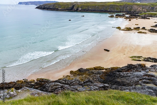 Fototapeta Panoramic viewpoint above Durness Beach, powerful waves crash against golden sand and striking rocks rise along the shore. A wild, breathtaking coastal scene in the heart of the Scottish Highlands.