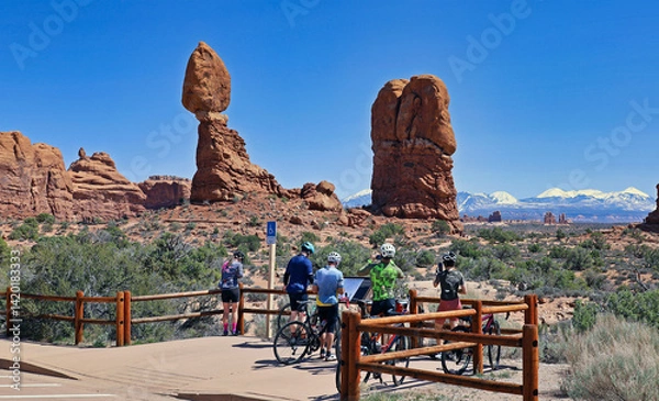 Fototapeta Bicycle tourists stop for a photo of Balanced Rock in Utah's Arches National Park