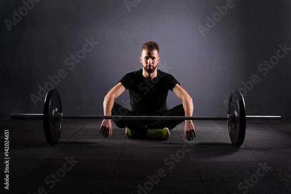 Obraz Handsome weightlifter preparing for training. Shallow depth of field, selective focus. Low key