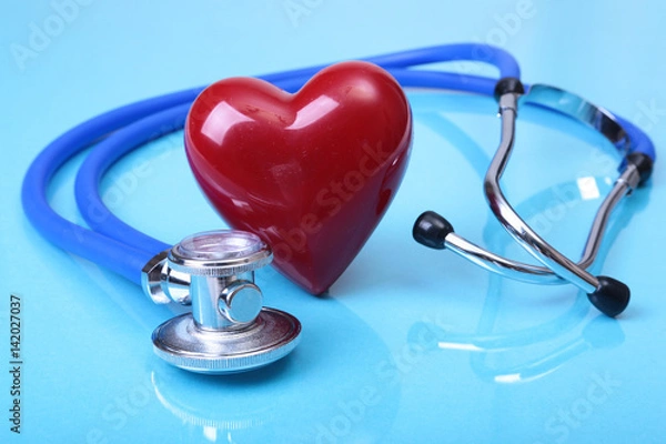 Obraz Medical stethoscope and red heart isolated on blue mirror background. you can place your text.