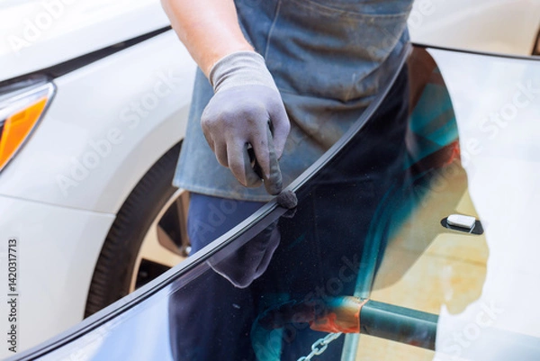 Obraz Technician fills applies adhesive car windshield fixes with resin at an auto repair shop