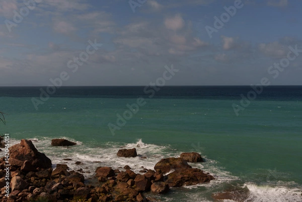 Obraz Turquoise water crashing gently on the rocks on a cloudy day. Zahara de los Atunes
