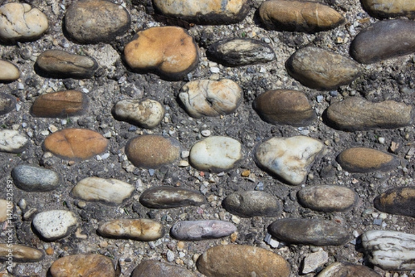 Fototapeta Close-up of cobblestone pavement texture with natural stones in dry soil