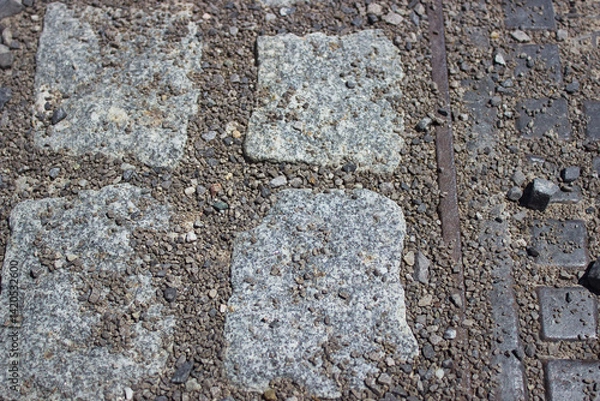 Fototapeta Granite cobblestones with gravel texture and iron line in pavement surface