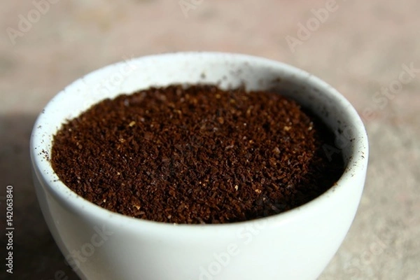 Obraz Closeup of grinded coffee beans in a small white cup
