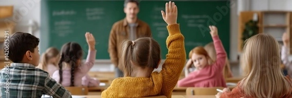 Fototapeta Elementary students raising hands in class