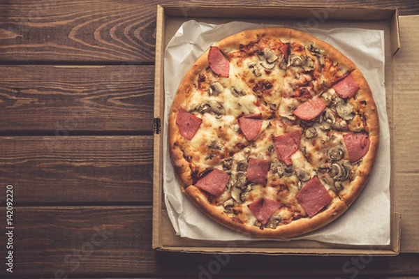 Obraz Top view of pizza in a box on wooden table with Mozzarella cheese, ham