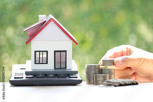 Fototapeta Calculating interest payments, Model house on calculator and stack of coins money on natural green background,Business investment and real estate concept