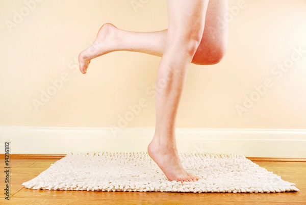Obraz A woman's naked legs standing on a bath mat