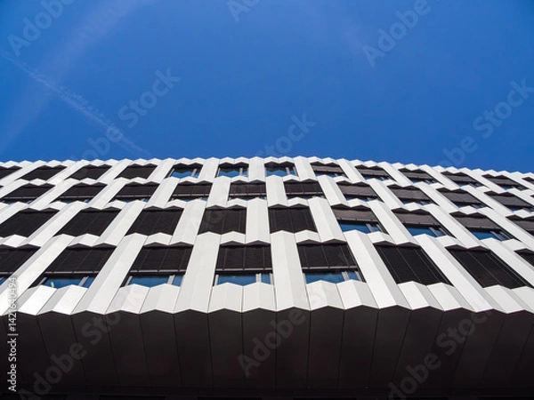 Obraz Modern building facade with geometric patterns against a clear blue sky.