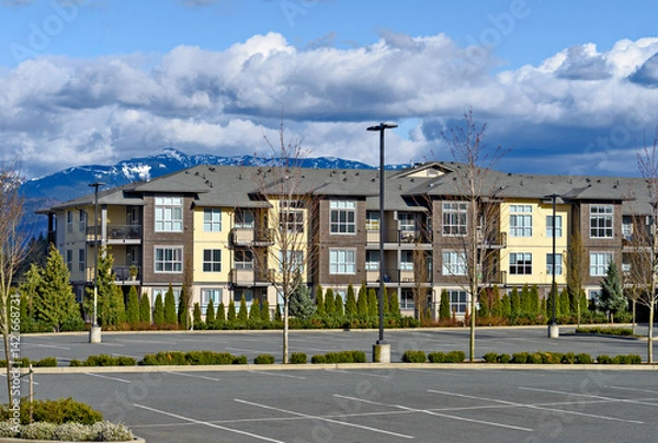 Obraz Low rise residential building with big parking lot in front on mountain background