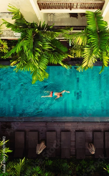 Fototapeta Aerial view of Active man, swimming in pool, drone view from above, Bali villa, tropical vacation, holiday on island hotel resort	
