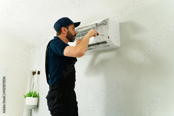 Fototapeta Technician repairing air conditioning unit with screwdriver
