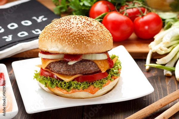 Obraz Big tasty burger on a white plate over wooden background.