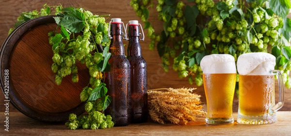 Obraz mug and glass of beer, green hops, bottles and beer barrel on wooden background