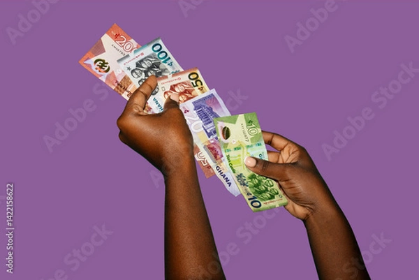 Obraz Black african hands holding various Ghanaian cedi notes overlapping each other in a line over purple background. closeup of Hands holding Ghana paper currencies