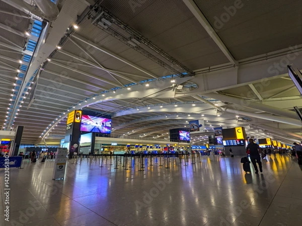 Fototapeta Travelers and staff navigate the modern, spacious Heathrow Airport Terminal 5 departure area in London