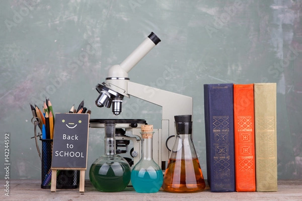 Fototapeta blackboard with text "Back to school", books, stationety and microscope