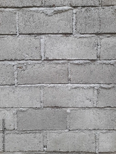Fototapeta A close-up view of a gray concrete brick wall, showcasing its rough texture and simple, industrial design.

