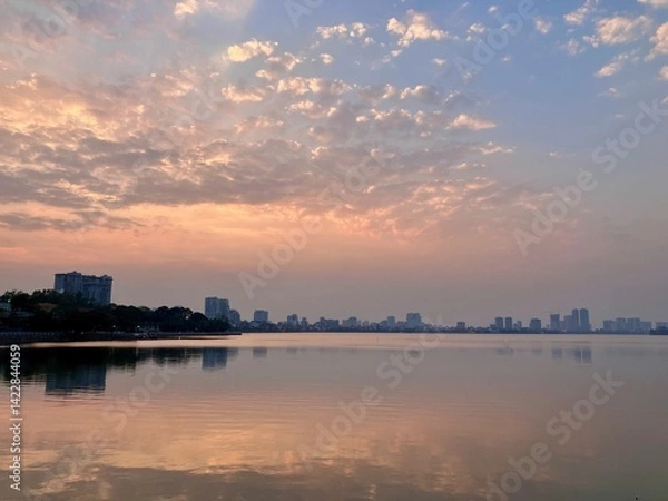 Fototapeta Pastel Urban Horizon: Soft Cloudscape Reflecting on Calm Waters on West Lake in Hanoi, Vietnam