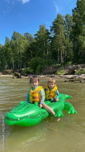 Fototapeta small children on an inflatable crocodile swim in the sea