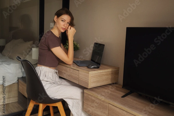 Fototapeta A girl works on a laptop at a table at home.