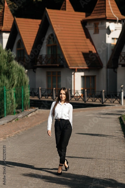 Fototapeta Girl in black pants on a cobbled path