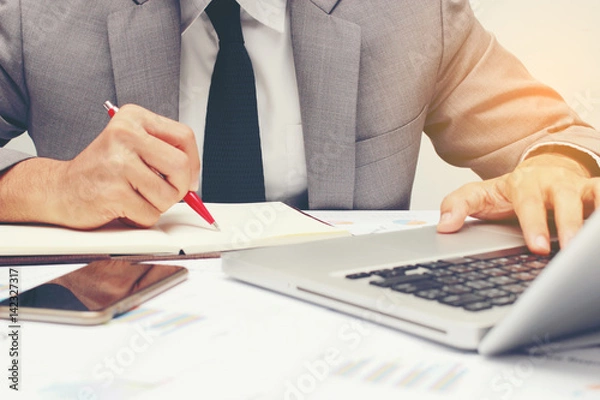 Fototapeta Business man working at office handing pen hand and writing message  with laptop and documents on his desk, consultant lawyer concept