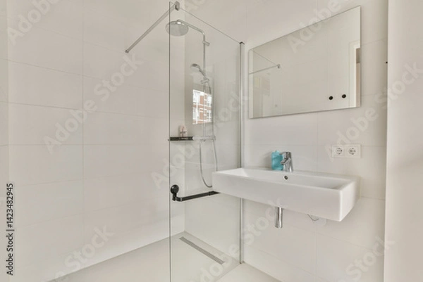 Fototapeta A pristine, modern bathroom featuring a sleek shower, a floating sink, and a large mirror. The clean lines and bright white tones create a serene environment.