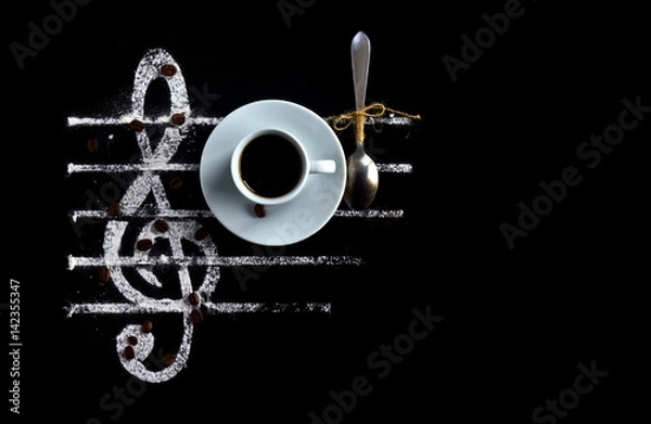 Fototapeta Black coffee in a cup with a spoon on a black background as a concept of musical notes