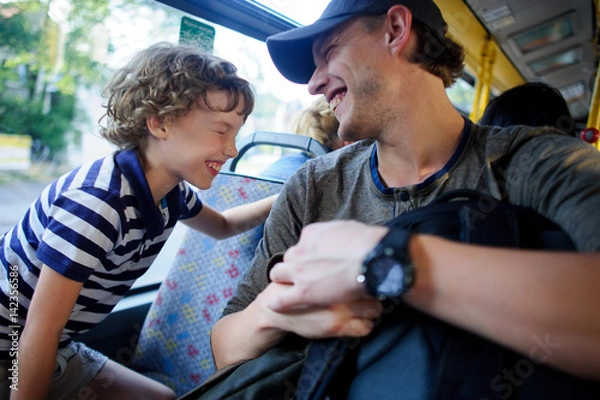 Fototapeta The young man goes by the bus together with the son.