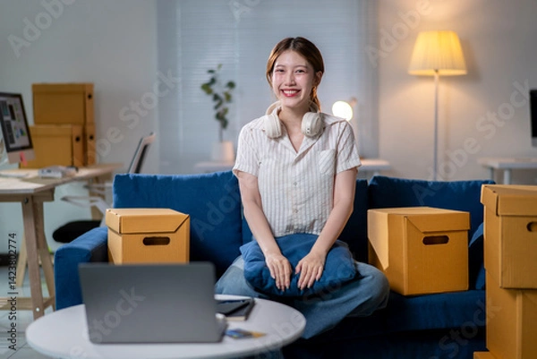 Fototapeta A woman is sitting on a couch with a laptop on a table in front of her