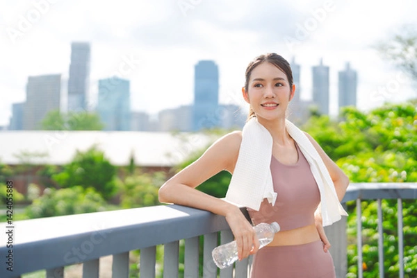 Fototapeta Southeast young asian woman rest form running cardio exercise with sweat towel mineral water