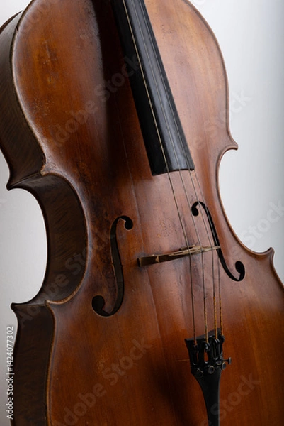 Fototapeta Detailed studio close-up of a classical cello showing the body and strings, photographed on a clean white background. The image highlights the fine wood grain, curved shape, and craftsmanship of the i